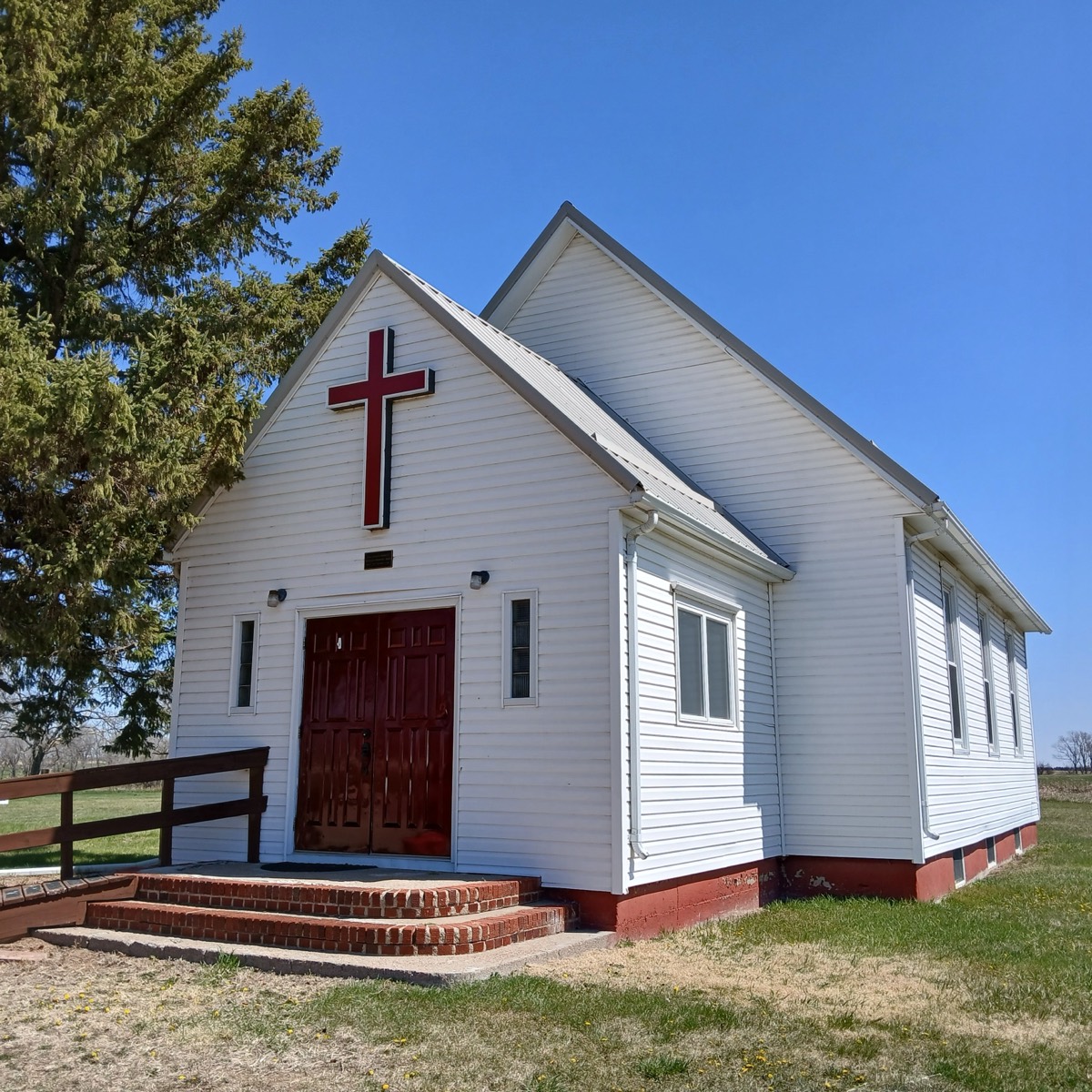 The Pleasant Valley Church building near Miller, South Dakota — a white clapboard church with a red cross and red doors under a clear blue sky